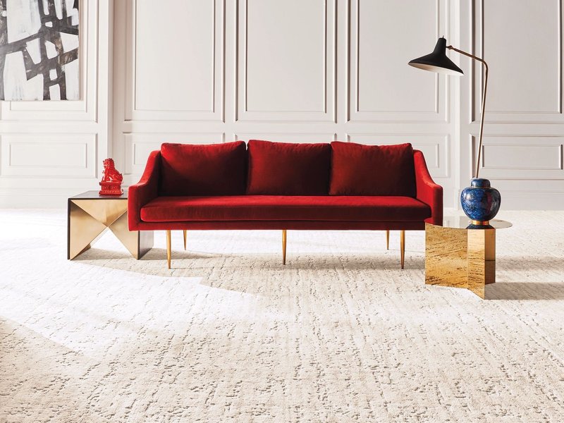Bright living room with a red velvet couch and beige textured carpet from Carpet Villa in Grand Rapids, MI